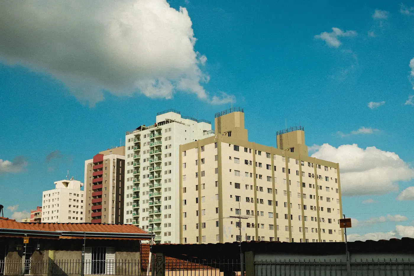 Cluster of mid-rise apartment buildings of varying heights under a blue sky with clouds.