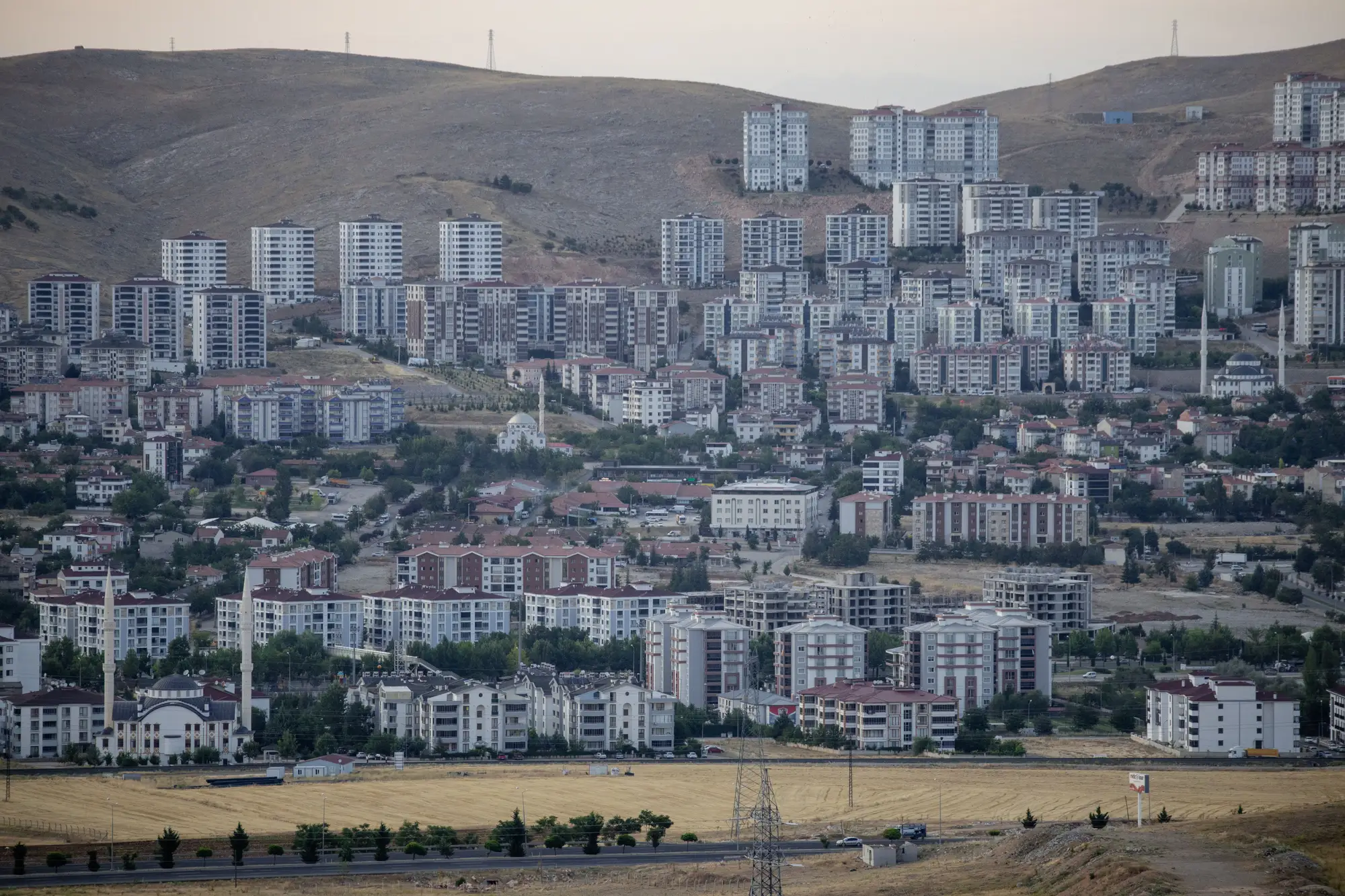 New apartment blocks climbing a bare hillside above an older town