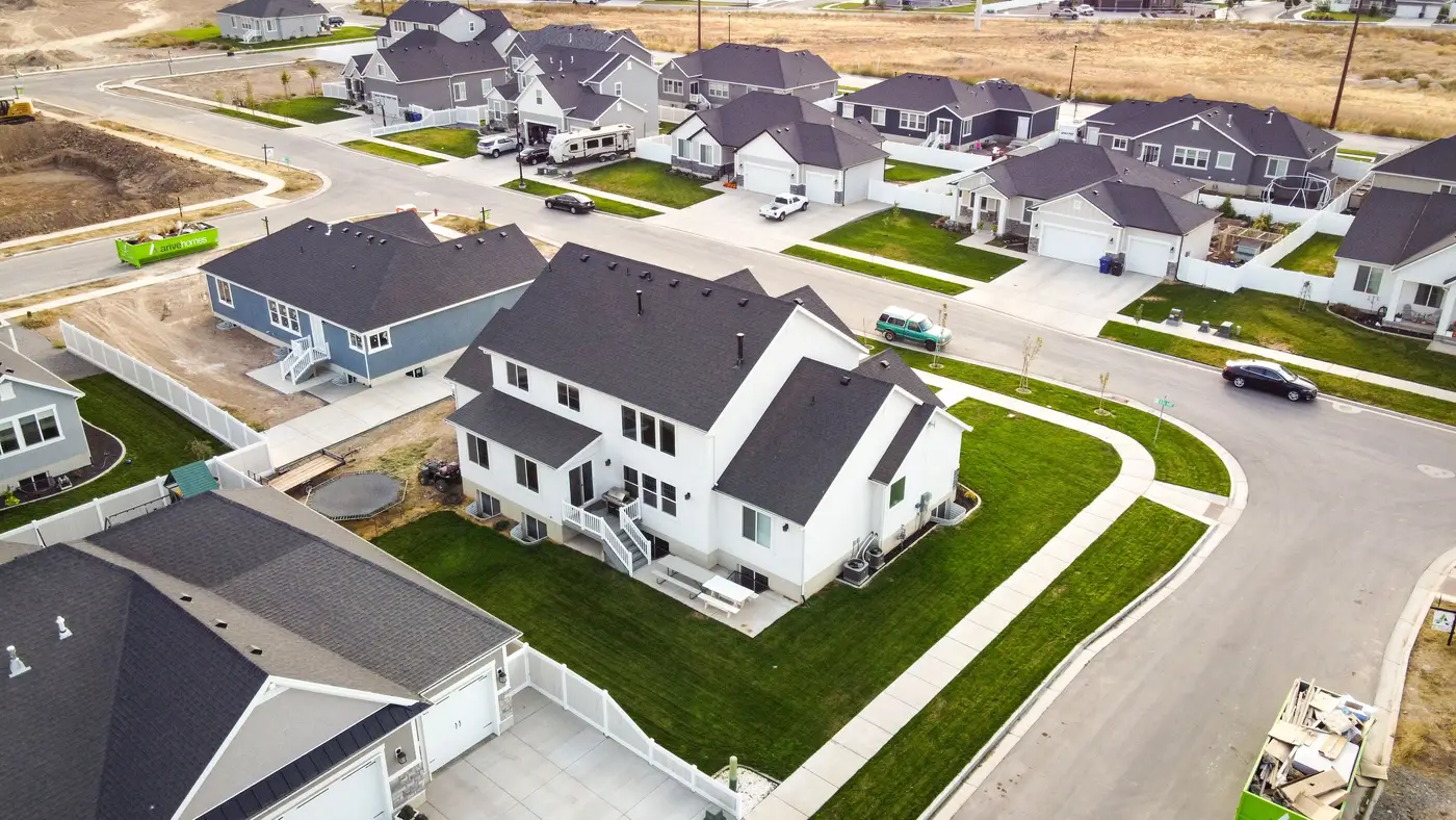 New single-family houses on a suburban street butting up against open, undeveloped land.